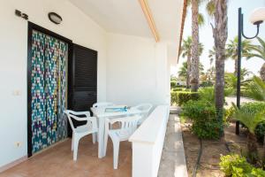 un patio con una mesa blanca, sillas y palmeras en Villaggio Club In en Vieste