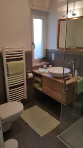 ein Badezimmer mit einem Waschbecken, einem WC und einem Spiegel in der Unterkunft viaDolceVita - Grüne Gästewohnung in Lana