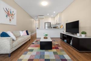 a living room with a couch and a flat screen tv at The Banq Apartments by Urban Rest in Sydney