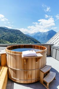 a hot tub on a roof with mountains in the background at Hotel Le V de Vaujany in Vaujany