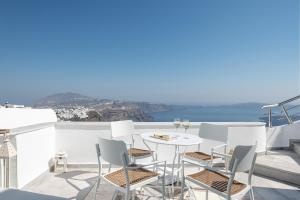 una mesa y sillas en un balcón con vistas al océano en Veranda View, en Imerovigli