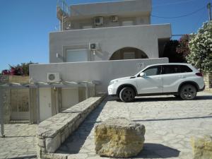 une voiture blanche garée devant une maison dans l'établissement Petaloudes, à Kamilárion