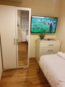 1 dormitorio con 1 cama y TV en la pared en Single Room G1 (Sandycroft Guest House) en Londres