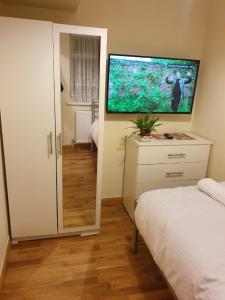 a bedroom with a bed and a television on the wall at Single Room G1 (Sandycroft Guest House) in London