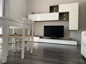 ein Wohnzimmer mit einem TV, einem Tisch und Stühlen in der Unterkunft Civico 14 in Reggio di Calabria