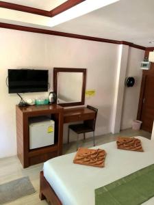 Cette chambre comprend un lit, un bureau et un miroir. dans l'établissement Grand Beach Resort, à Koh Tao