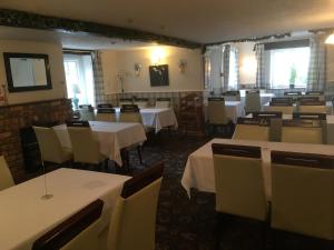 un comedor con mesas y sillas con mantel blanco en The New Inn, en Oswestry