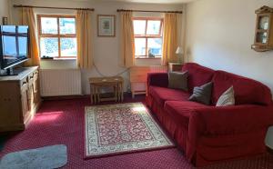 a living room with a red couch and a tv at Fox and Hounds Cottage, Starbotton in Starbotton