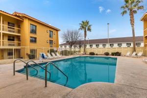 a swimming pool in front of a building with palm trees at La Quinta Inn by Wyndham El Paso West in El Paso