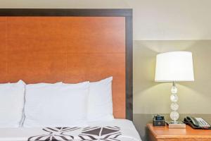 a bed with a wooden headboard and a lamp and a phone at La Quinta by Wyndham Oklahoma City - Moore in Moore