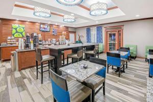a restaurant with a bar and tables and chairs at La Quinta by Wyndham Oklahoma City - Moore in Moore