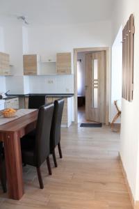 a kitchen with a wooden table and black chairs at Pogácsás Apartman in Tokaj