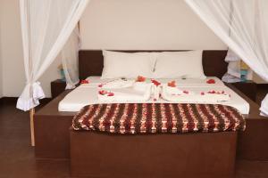 a bed with white sheets and decorations on it at Shamba Village in Paje