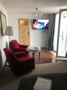 a living room with two red chairs and a tv at Flores Apartament in Katowice