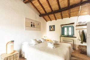 two beds in a room with white walls and a wooden ceiling at Sa Crai B&B - Sardinian Experience in Lotzorai