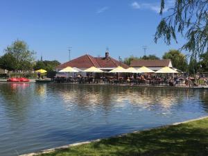 een restaurant met tafels en parasols naast een meer bij Villa Domus XIX in Tongeren