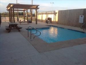 a swimming pool with a swing and a gazebo at PetroStay Inn & Suites Cotulla in Cotulla
