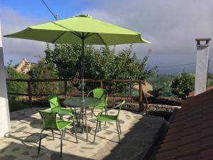 einen Tisch und Stühle mit einem grünen Sonnenschirm auf einer Terrasse in der Unterkunft La Zamora in Guarazoca