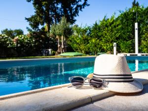 a hat and sunglasses sitting next to a swimming pool at Cypress Garden Villas in Svoronata