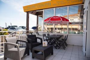 een restaurant met een tafel en stoelen en een parasol bij Hotel Les Dunes in La Tranche-sur-Mer