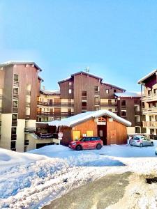 two cars parked in a parking lot in front of a building at Appartement chaleureux au pied des pistes, 4 personnes, wifi in Val Thorens