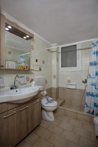 Un baño con inodoro, lavabo y espejo. en Elalia Apartments, en Hersonissos