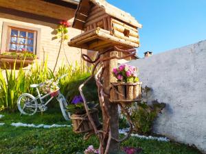 a bird house with flowers and a bike in a yard at Canquerini Chalés in Monte Verde
