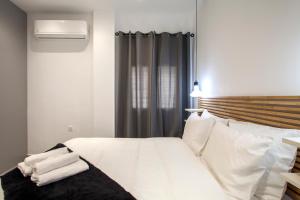 Schlafzimmer mit einem Bett mit weißer Bettwäsche und Kissen in der Unterkunft Emfasis Loft Spacious and Elegant Heraklion in Iraklio