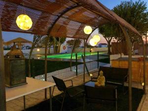 a woman sitting on a table under a pavilion with a pool at Villas Santa Ana in Conil de la Frontera