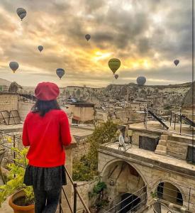 a woman standing on a balcony looking at hot air balloons at Aydinli Cave Hotel in Göreme