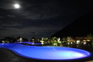 ein blauer Pool in der Nacht mit dem Mond am Himmel in der Unterkunft Ortano Mare Resort in Rio Marina