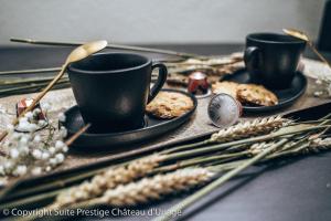 une table recouverte de deux tasses et d'assiettes de nourriture dans l'établissement Suite Prestige Château Uriage - Escapade romantique, à Saint-Martin-dʼUriage