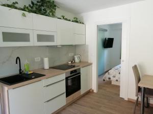 a kitchen with white cabinets and a sink and a bed at Apartmaji Iris Kobarid in Kobarid