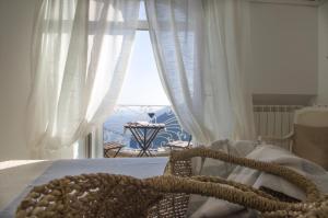 a bedroom with a bed with white curtains and a window at Casa Romelide Positano Amazing view, free parking along the street, free breakfast basket in Positano