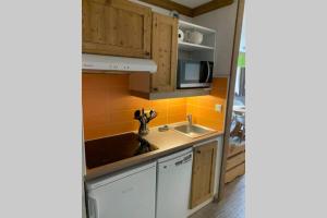 a kitchen with a sink and a microwave at STUDIO CHALETS DE SOLAISE in Val dʼIsère +2 photos
