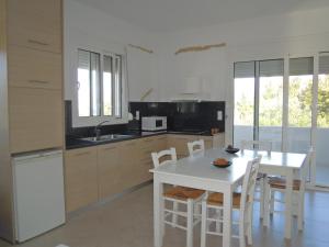 a kitchen with a table and a white table and chairs at Petaloudes in Kamilari