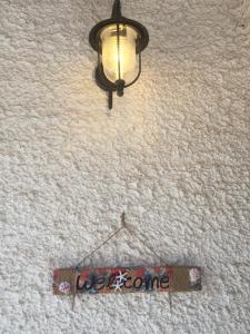 a light on a wall with a sign on it at Rose’s place in Artemida