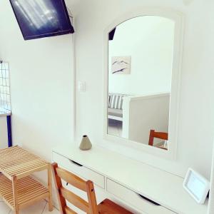 a white dresser with a mirror and a chair at Spanos Apartments in Agios Petros
