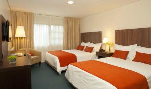 una habitación de hotel con 2 camas y una silla en Hotel Bahia Redonda en El Calafate