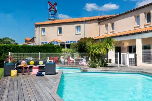 a swimming pool in front of a building at Logis Hôtel L'Air Marin in Yves