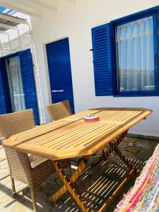 a wooden table with chairs and a blue door at Spanos Apartments in Agios Petros