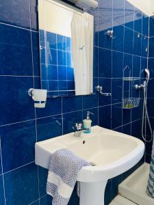 a blue tiled bathroom with a sink and a mirror at Spanos Apartments in Agios Petros