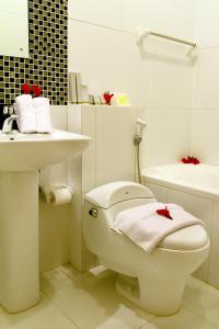 a white bathroom with a white toilet and a sink at Grand Royal BIL Hotel in Praya