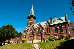 a large brick church with a steeple on a hill at Welcome in Authuille
