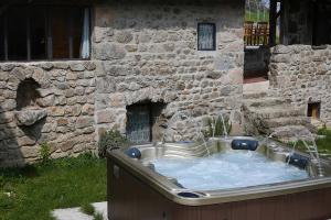 bañera de hidromasaje frente a un edificio de piedra en Les Gîtes du Couvent en Ardèche - Gîte de groupe en Nozières
