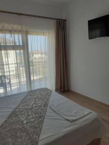 a bedroom with a large bed and a large window at VILA IRINA in Mangalia