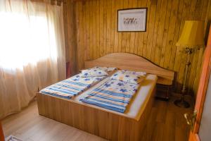 a bed in a bedroom with a wooden wall at Pensiunea Trei Ponei in Corbeni +119 photos