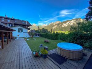 a hot tub on a wooden deck with mountains in the background at Family B&B Le Vieux Chalet in Chateau-d'Oex