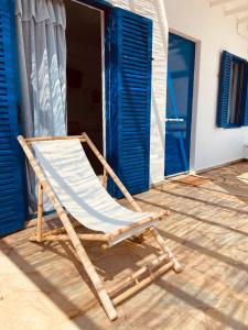 a folding chair sitting on a porch with blue doors at Spanos Apartments in Agios Petros