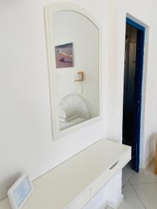 a mirror on a white wall above a white bench at Spanos Apartments in Agios Petros